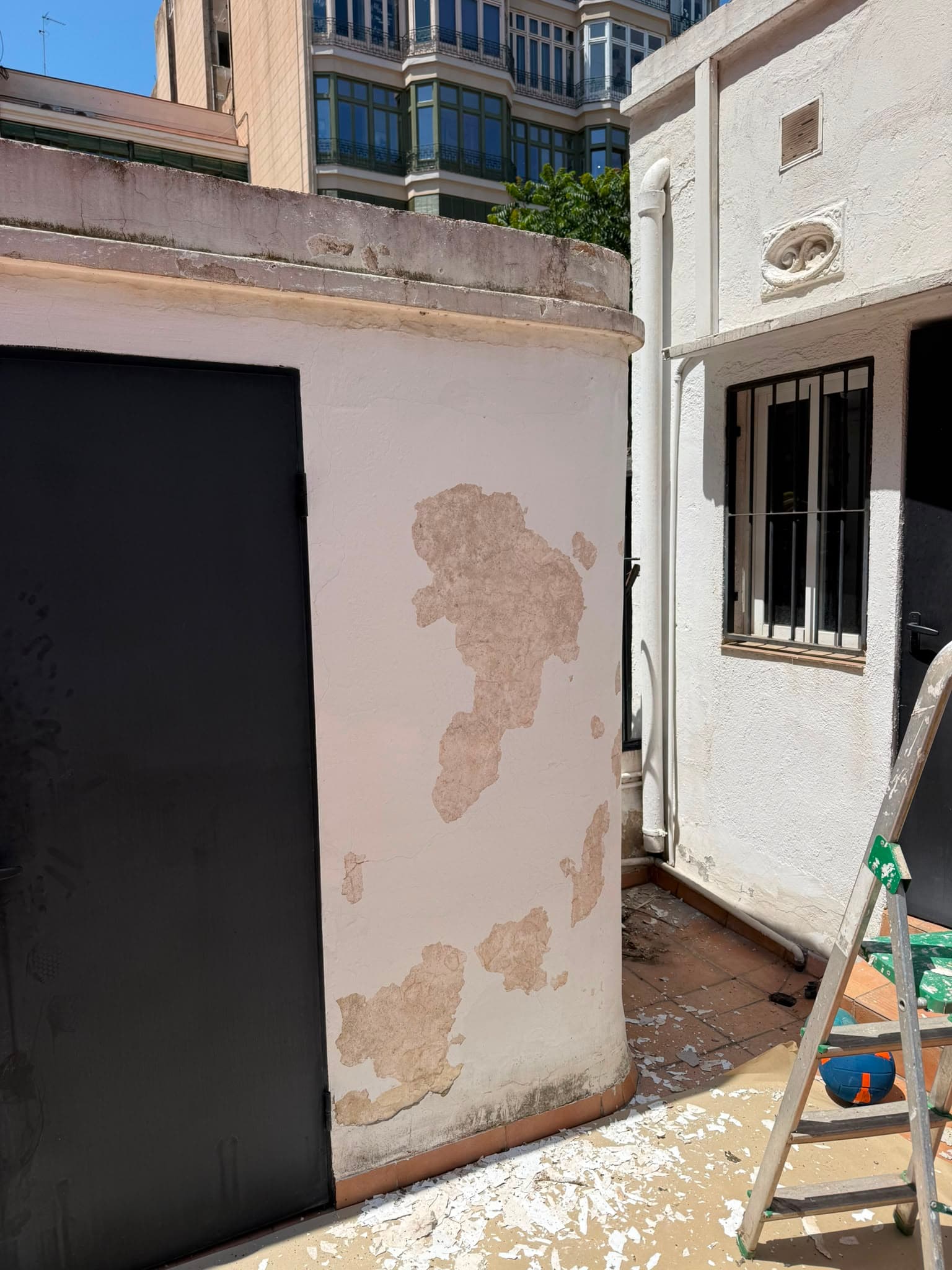 Muro de terraza con la pintura desconchada y el revoco a la vista antes de la reparación