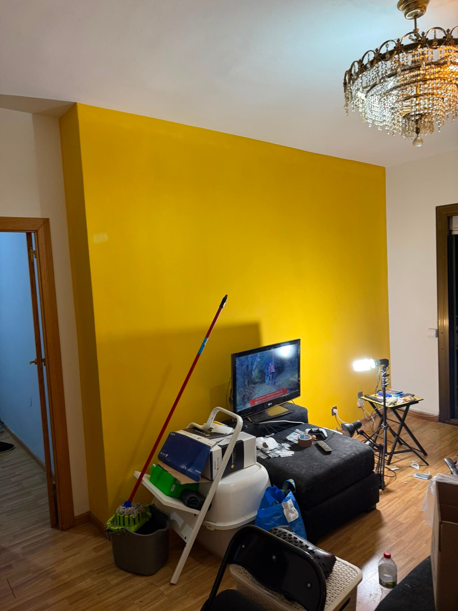Salón pintado por Barcelona Solutions con una pared en amarillo y el resto en blanco